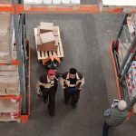 High angle view of warehouse workers organizing and preparing shipments with boxes and pallets.
